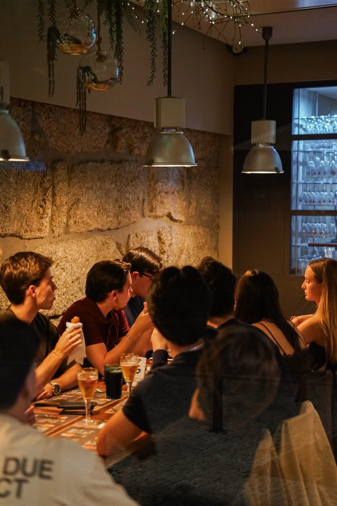 A group of friends sharing a long table at Capa na Baixa, Porto